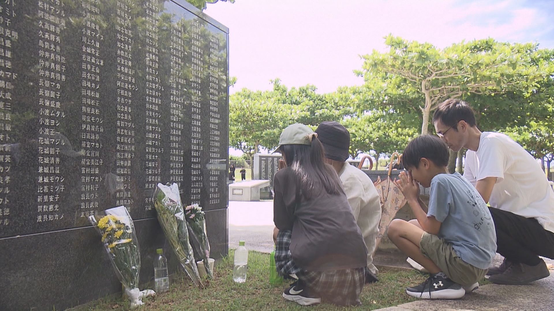 慰霊碑の前で手を合わせる人々